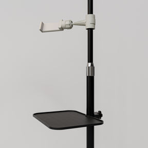 Close-up of the black Manufakturo accessory tray clamped to a treatment lamp stand