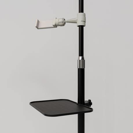 Close-up of the black Manufakturo accessory tray clamped to a treatment lamp stand