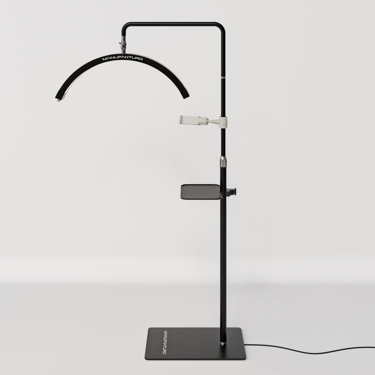Full view of a black Manufakturo treatment lamp with the accessory tray fitted to the stand