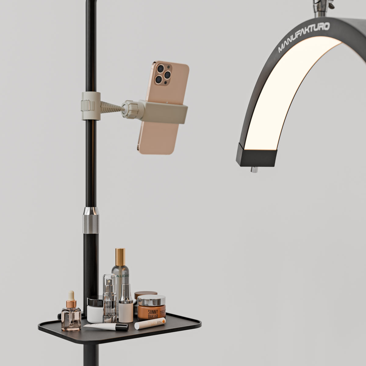 Black Manufakturo accessory tray holding bottles and jars beside a treatment lamp with a phone in its holder