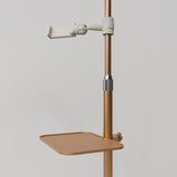 Close-up of the gold Manufakturo accessory tray clamped to a treatment lamp stand