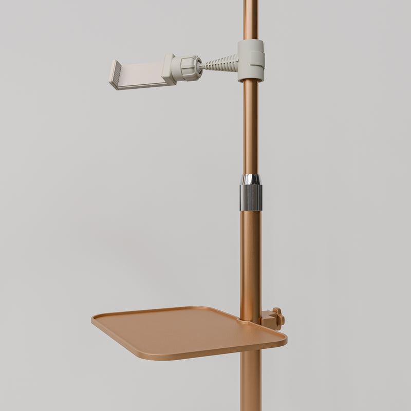 Close-up of the gold Manufakturo accessory tray clamped to a treatment lamp stand