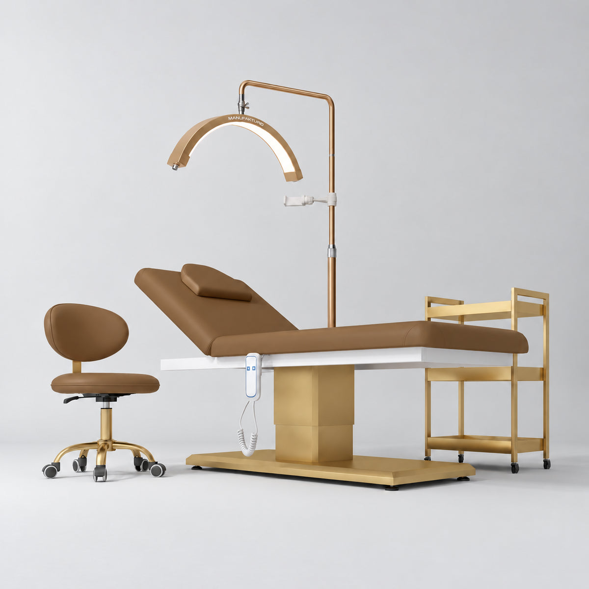 Manufakturo Chérie Caramel four-piece salon set with treatment bed, matching salon chair, V3 Pro Gold lamp and empty gold three-tier beauty trolley.