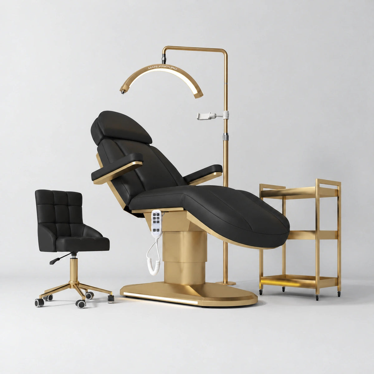 Manufakturo Étoile Black complete studio set with electric beauty bed, Noblesse chair, gold trolley and V3 Pro Gold treatment lamp with an aligned stand on the original grey studio background.