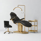 Manufakturo Étoile Black complete studio set with electric beauty bed, Noblesse chair, gold trolley and V3 Pro Gold treatment lamp with an aligned stand on the original grey studio background.