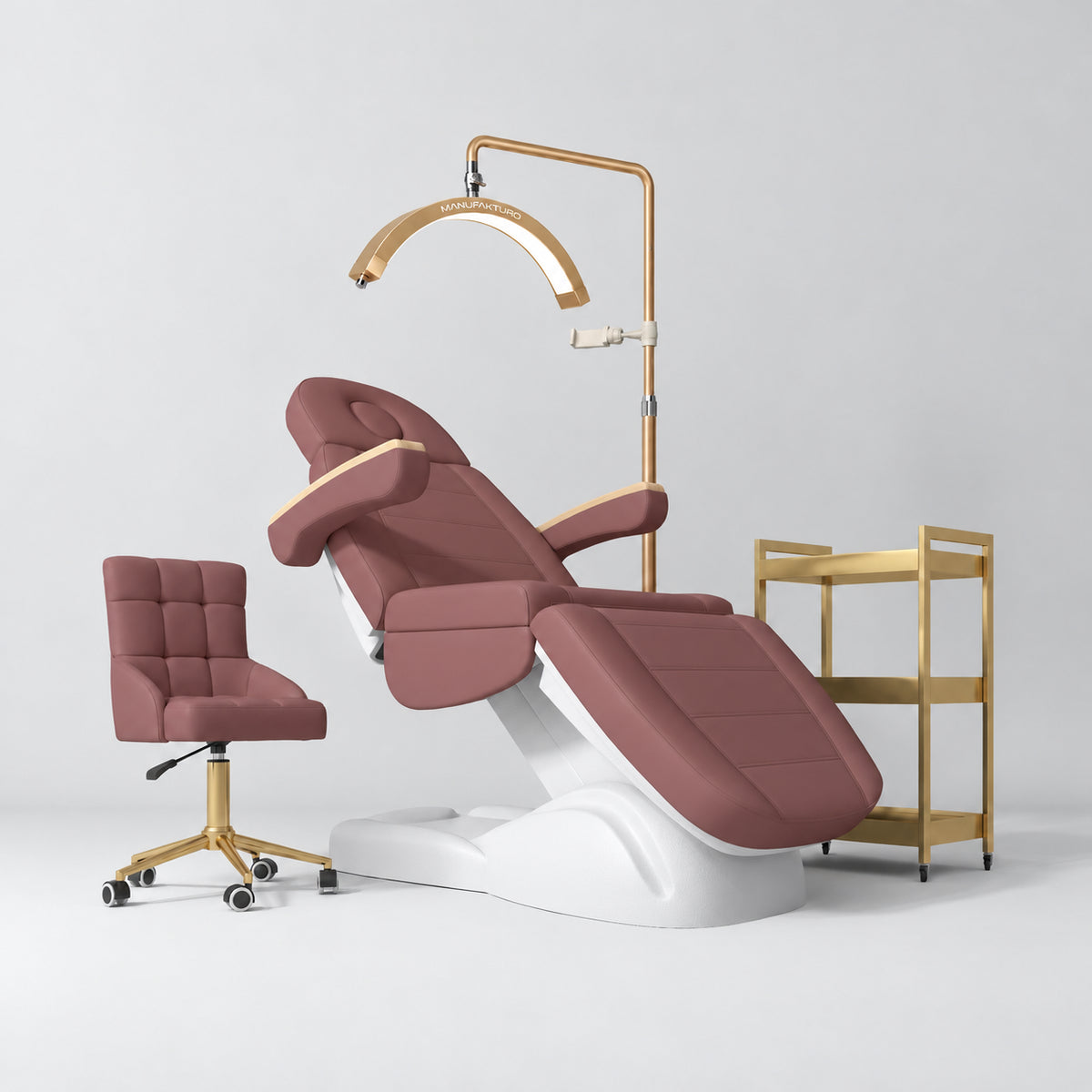Manufakturo Grace Dusty Rose four-piece salon set with treatment bed, matching salon chair, V3 Pro Gold lamp and empty gold three-tier beauty trolley.