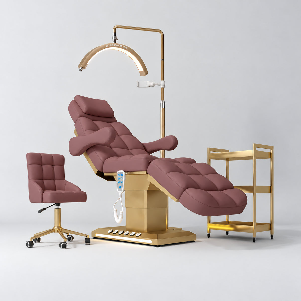 Manufakturo Orielle B Dusty Rose four-piece salon set with treatment bed, matching salon chair, V3 Pro Gold lamp and empty gold three-tier beauty trolley.