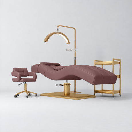 Manufakturo Prestige Dusty Rose four-piece salon set with treatment bed, matching salon chair, V3 Pro Gold lamp and empty gold three-tier beauty trolley.