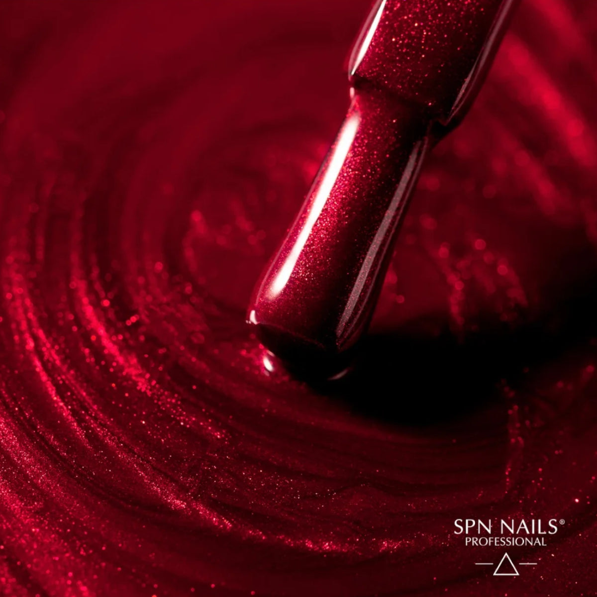 Brush dipped in SPN Nails UV/LED Gel Polish 1023 Kiss the Star, spreading vibrant red glitter polish on a glossy surface.