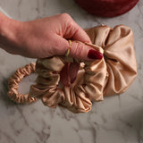 Roxie Cosmetics Luxe 100% Mulberry Silk 30 Momme Scrunchie Beige - product displayed with its packaging on a dark background